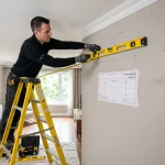 Technician measuring and levelling a wall to mount a ductless mini-split unit