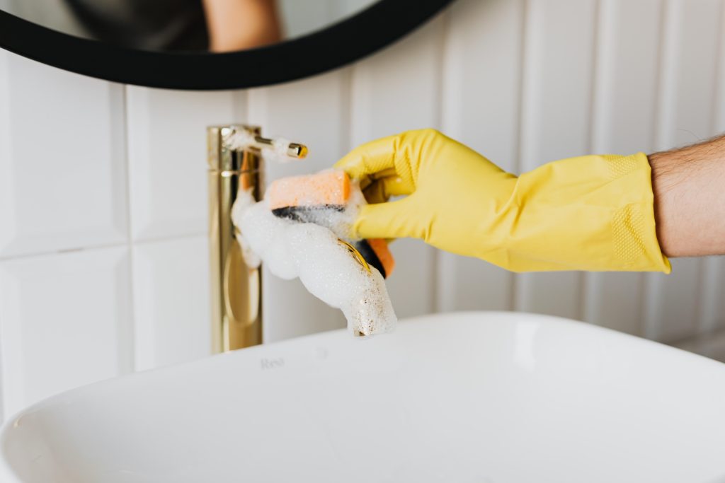 A gloved hand cleaning the faucet
