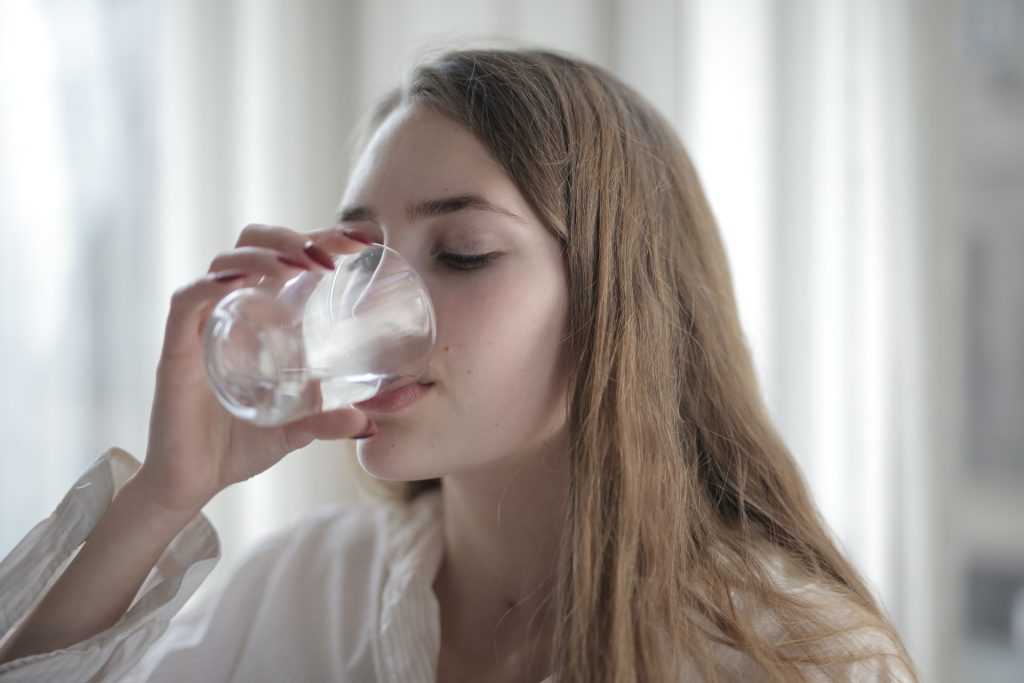 A woman drinking a glass of soft water
