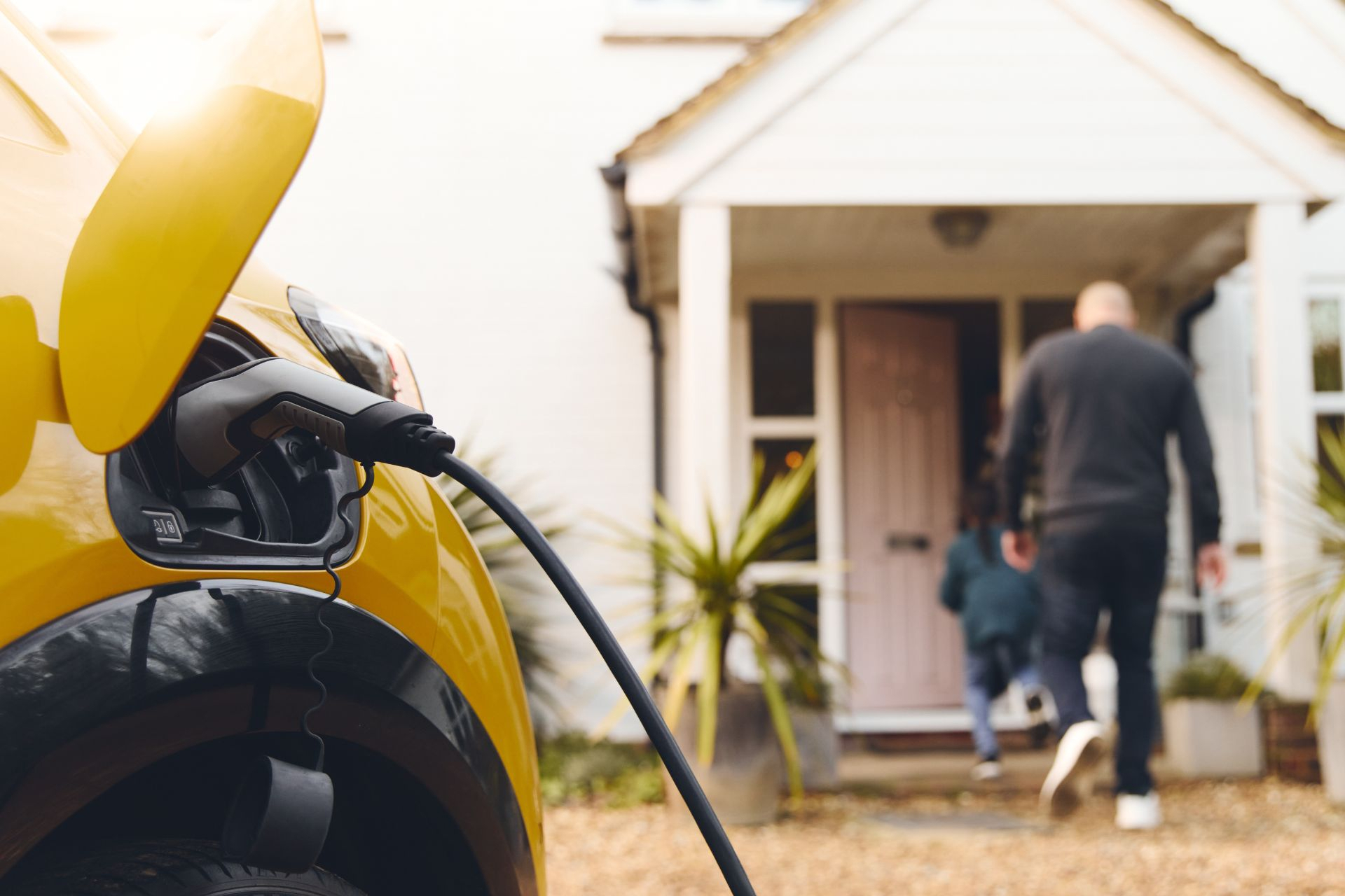 A Man Charges His Yellow Electric Car In His Home’s Driveway - LG Home Comfort