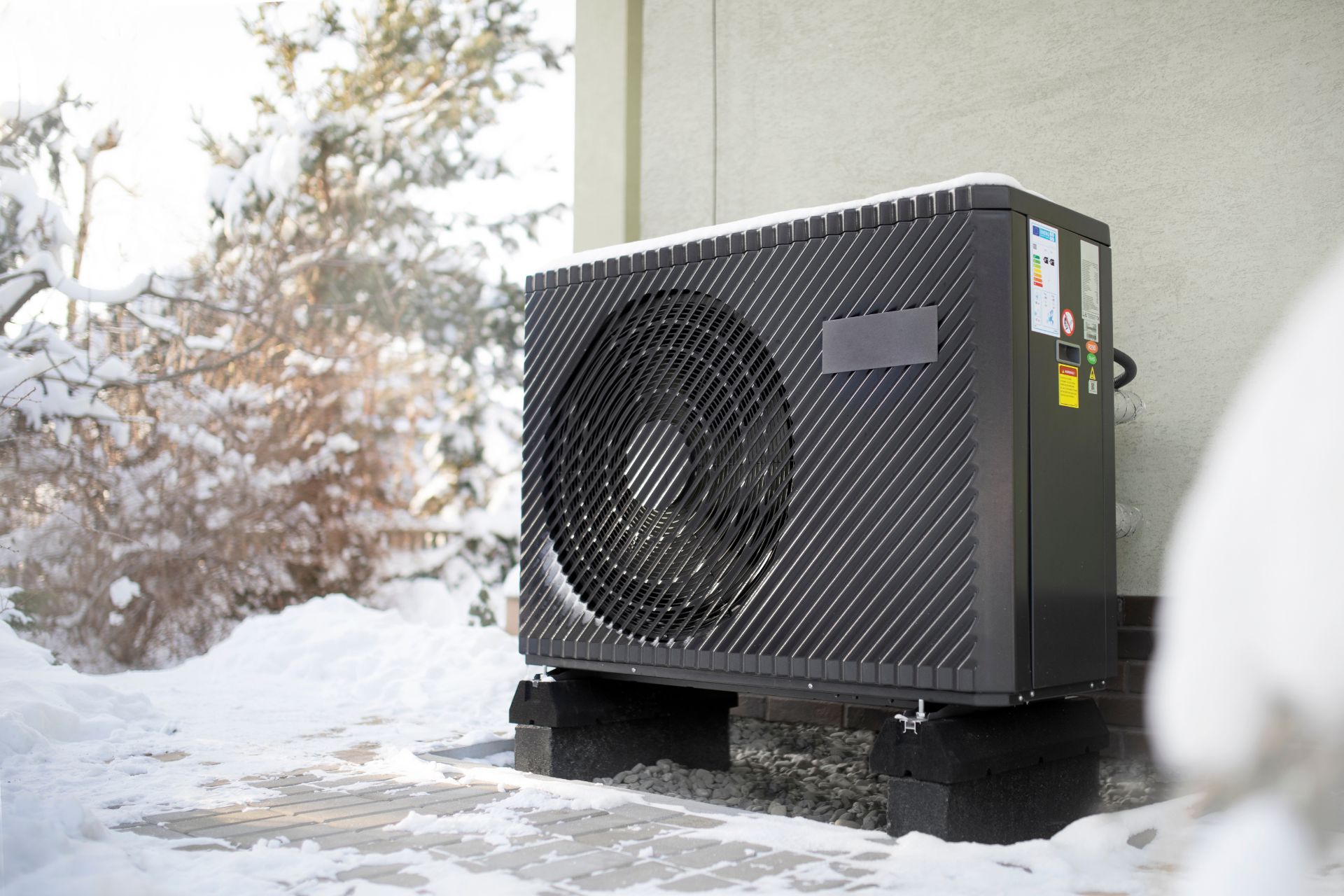 An outdoor air source heat pump unit surrounded by ice and snow