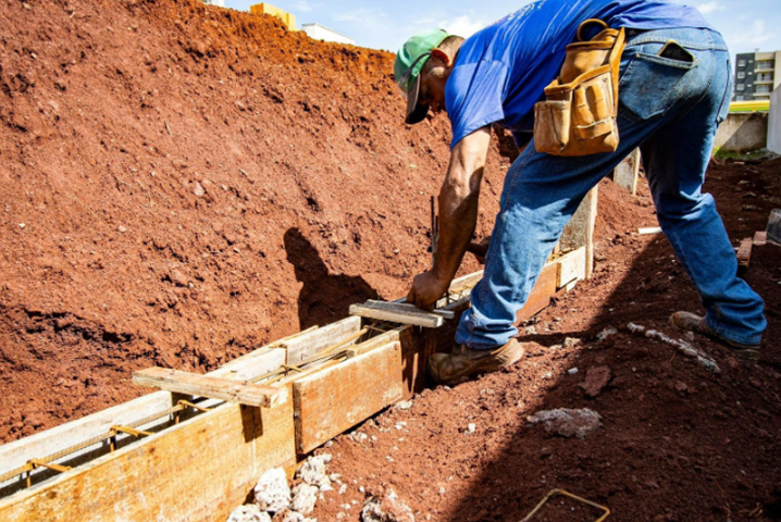A construction worker building barriers to divert water and prevent it from pooling around the basement.