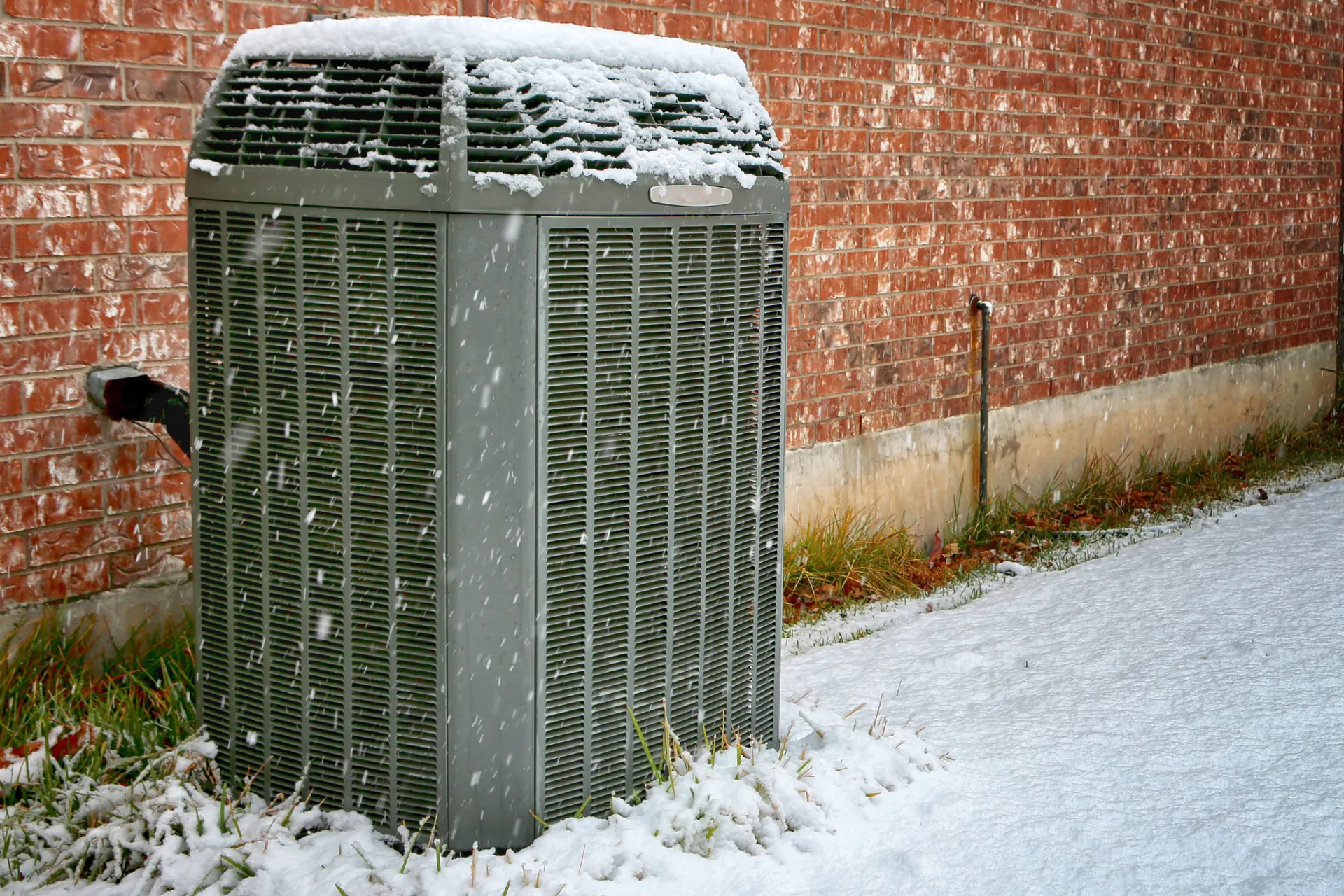 Central air conditioner condenser unit under falling snow