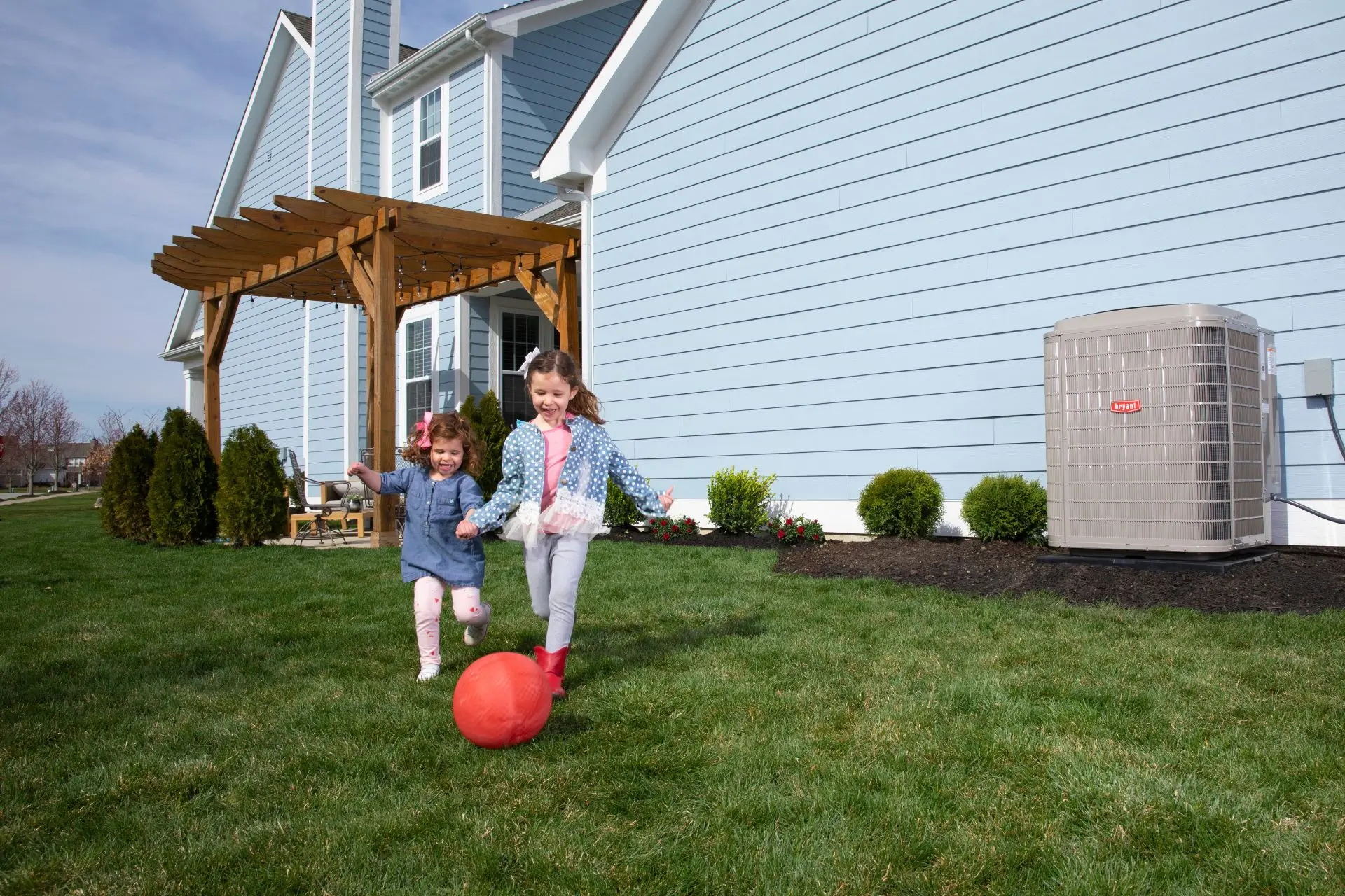 Two kids playing outside near an HVAC unit mounted outdoors
