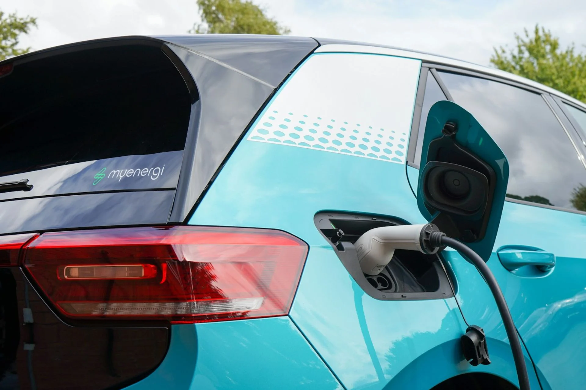 A blue electric car hooked up to a charging point