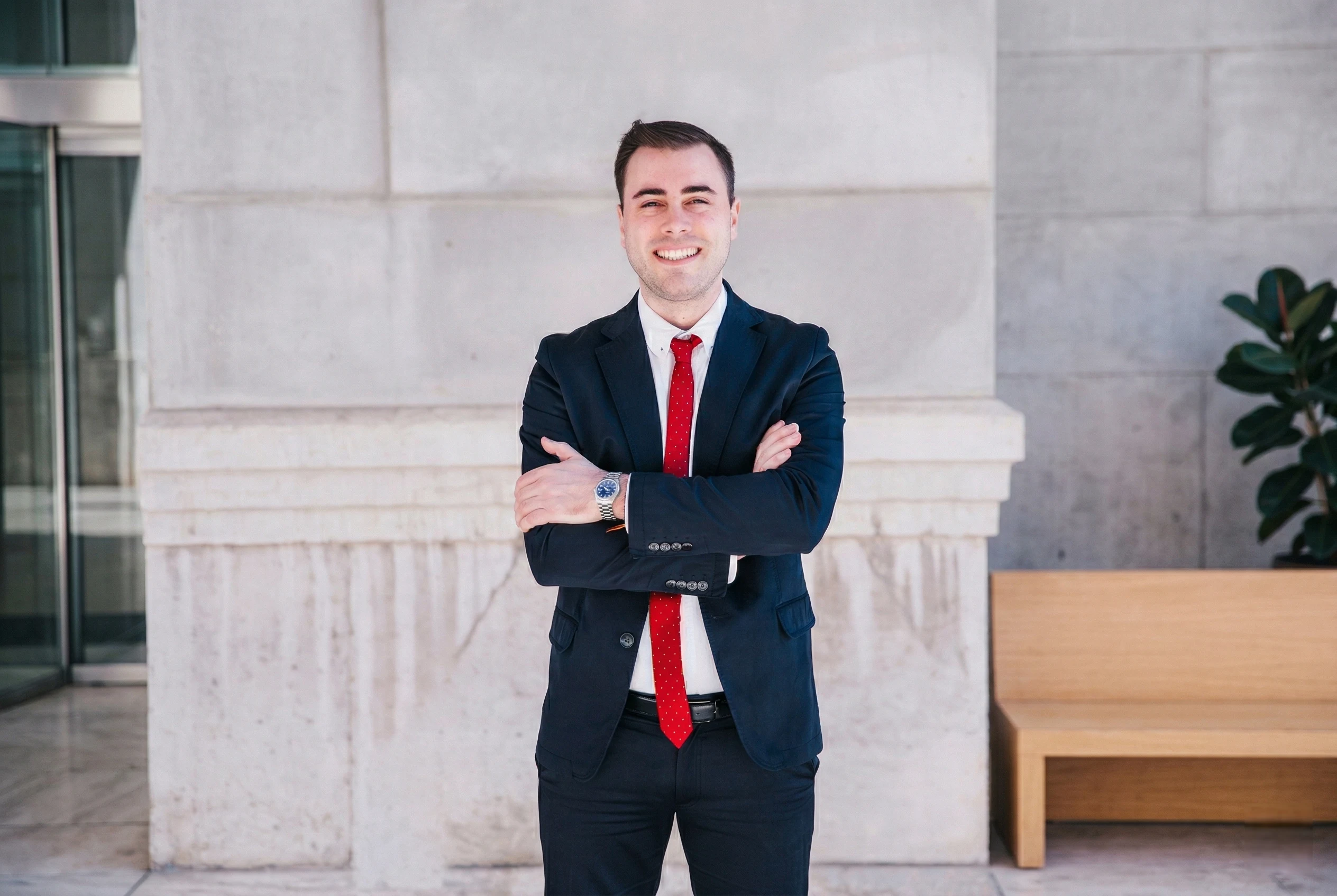 Man in navy suit standing outside an office building.